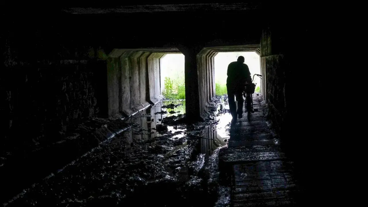 Mroczny tunel, błoto i woda. Postać z rowerem wychodzi ku światłu. Czy to początek drogi przez nawiedzone miejsca w Polsce?