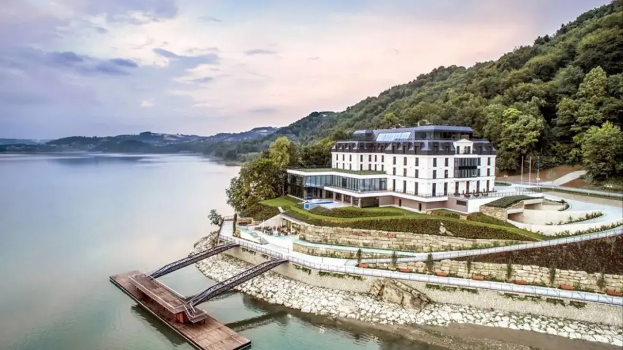 Elegancki hotel nad jeziorem, idealny na romantyczne miejsca w Polsce. Widok na spokojną taflę wody i zielone wzgórza.