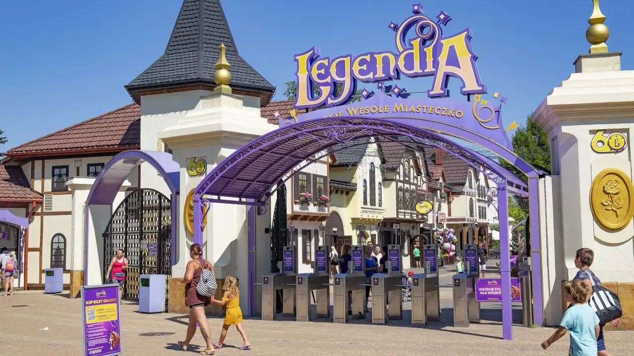 Wejście do Legendia Wesołe Miasteczko w Chorzowie. Rodziny wchodzą przez bramki, słońce świeci.
