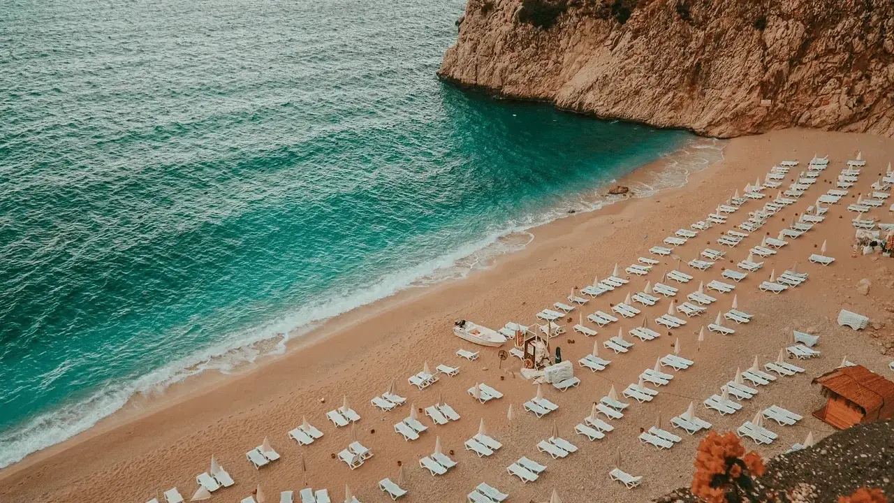 Piękna plaża z turkusową wodą i rzędami leżaków. Idealne miejsce, by zastanowić się, gdzie na wakacje.