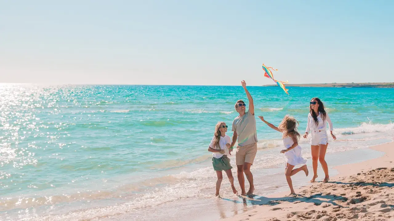 Rodzina puszcza latawiec na plaży. Idealne miejsce, gdzie nad morze z dziećmi tanio i radośnie spędza czas.