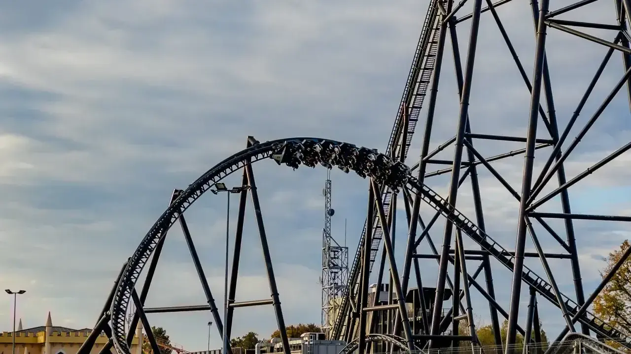 Pasażerowie jadą na wagonikach największego rollercoastera w Europie, który pnie się po stalowej konstrukcji.