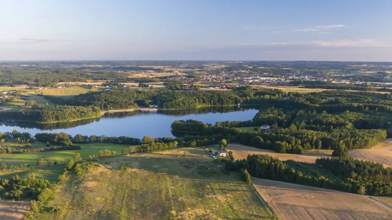 Malownicze jezioro otoczone lasami, z miasteczkiem w tle. Idealne miejsce na rodzinne wycieczki i odkrywanie bytów atrakcji dla dzieci.