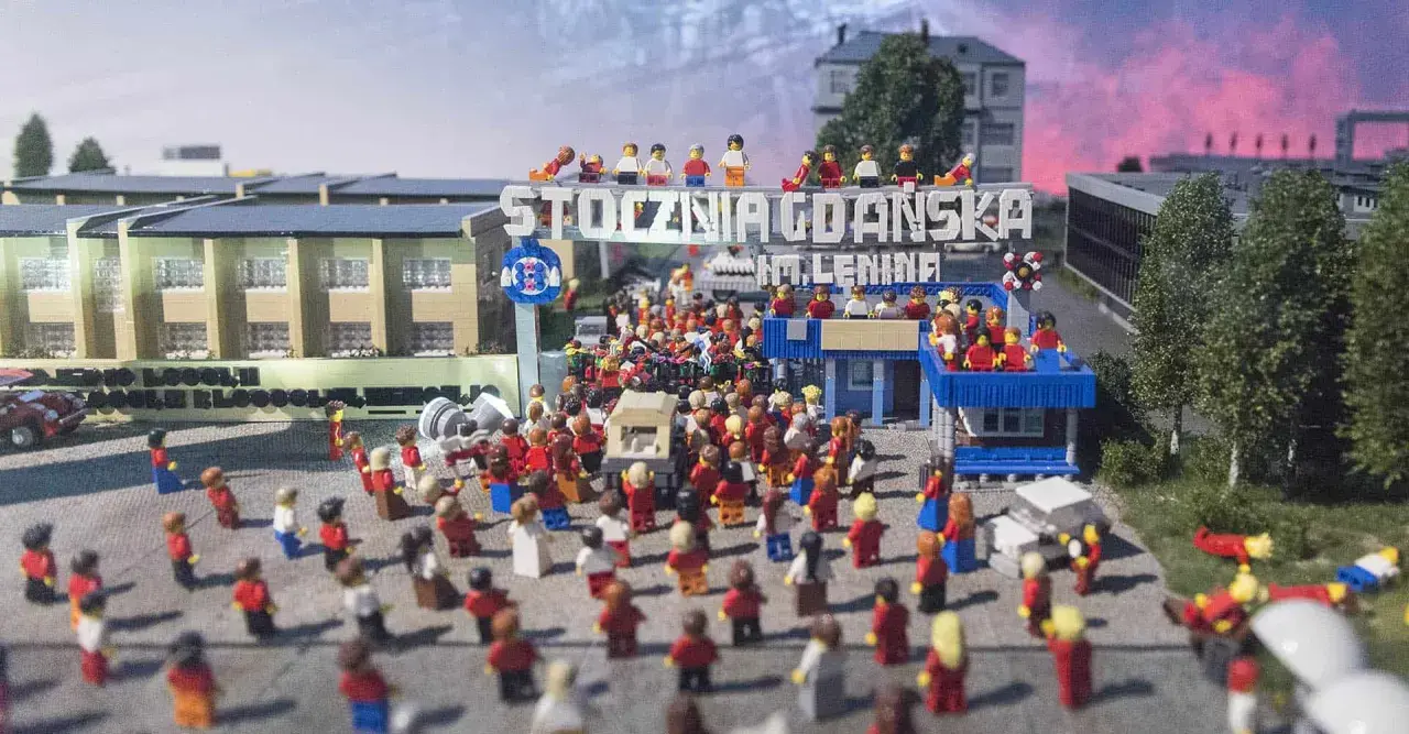 Miniaturowa scena z Klockoland Kraków przedstawiająca tłum ludzi pod bramą z napisem "Stocznia Gdańska im. Lenina".