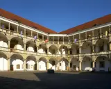 Dziedziniec zamku w Brzegu z arkadowymi krużgankami, kolumnami i flagami. Zamek w Brzegu ciekawostki – piękna renesansowa architektura.