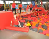 Dzieci bawią się w basenie z gąbkami w Flypark Kielce. Jeden chłopiec w czerwonej koszulce próbuje wstać, a drugi w żółtej wspina się po gąbkach.