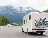Kamperem nad morze, z rowerami na bagażniku, jedzie autostradą w górach.