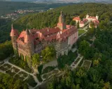 Zamek Książ otoczony zielenią, z widokiem na okoliczne wzgórza i miasteczko.