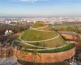 Kopiec Kościuszki w Krakowie, wspaniałe miejsce na darmowe atrakcje Kraków. Widok z lotu ptaka na zielony kopiec z krętymi ścieżkami i panoramę miasta.