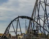 Pasażerowie jadą na wagonikach największego rollercoastera w Europie, który pnie się po stalowej konstrukcji.
