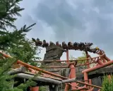 Kolejka górska w Legoland Polska pędzi po torach wśród zieleni i skalnych formacji.