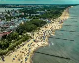 Tłum ludzi na plaży w Mielnie, cieszących się słońcem i morzem. To popularne **Mielno atrakcje** turystyczne.