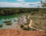 Polskie Malediwy, gdzie można się kąpać. Turkusowa woda, drewniane molo wijące się po jeziorze, otoczone lasem. Ludzie odpoczywają i kąpią się.