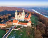 Wielki klasztor na wzgórzu, niczym milczący zakonnik, wita pierwsze promienie słońca. Obok rzeka i miasto w oddali.