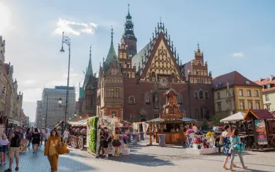 Wrocławski Rynek tętni życiem, idealne miejsce na weekendowy wypad. Ludzie spacerują, podziwiając zabytkową architekturę i kolorowe stragany.