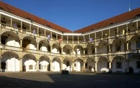 Dziedziniec zamku w Brzegu z arkadowymi krużgankami, kolumnami i flagami. Zamek w Brzegu ciekawostki – piękna renesansowa architektura.