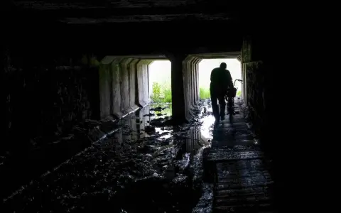 Mroczny tunel, błoto i woda. Postać z rowerem wychodzi ku światłu. Czy to początek drogi przez nawiedzone miejsca w Polsce?