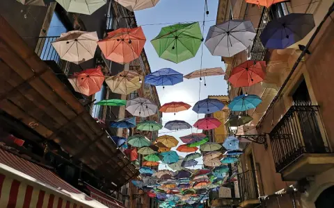 Kolorowe parasole nad ulicą w Katanii. Wspaniała instalacja, którą warto zobaczyć, tworzy magiczną atmosferę.