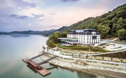 Elegancki hotel nad jeziorem, idealny na romantyczne miejsca w Polsce. Widok na spokojną taflę wody i zielone wzgórza.