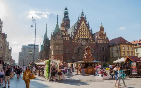 Wrocławski Rynek tętni życiem, idealne miejsce na weekendowy wypad. Ludzie spacerują, podziwiając zabytkową architekturę i kolorowe stragany.