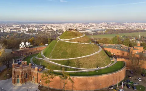 Kopiec Kościuszki w Krakowie, wspaniałe miejsce na darmowe atrakcje Kraków. Widok z lotu ptaka na zielony kopiec z krętymi ścieżkami i panoramę miasta.