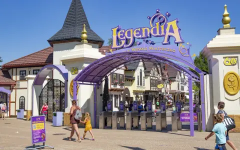 Wejście do Legendia Wesołe Miasteczko w Chorzowie. Rodziny wchodzą przez bramki, słońce świeci.