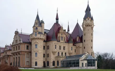Zamek Książ, jeden z najpiękniejszych zamków w Polsce, z charakterystycznymi wieżami i czerwonymi dachami, otoczony zielenią.