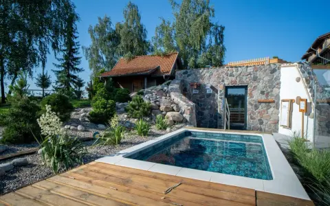 Relaks w polskim spa: basenik, kamienna ściana z wejściem do sauny i urokliwy ogród. Idealne miejsce na odpoczynek.