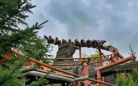 Kolejka górska w Legoland Polska pędzi po torach wśród zieleni i skalnych formacji.