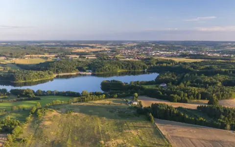 Malownicze jezioro otoczone lasami, z miasteczkiem w tle. Idealne miejsce na rodzinne wycieczki i odkrywanie bytów atrakcji dla dzieci.