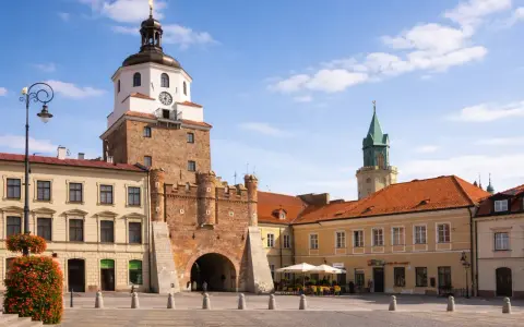 Brama Krakowska w Lublinie, symbol miasta, zaprasza do odkrywania lublin nietypowe atrakcje. W tle wieża zamkowa i kamienice.