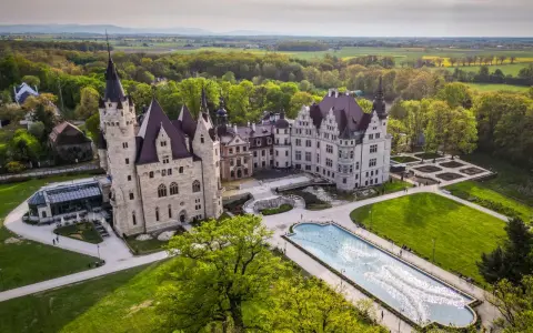 Majestatyczny pałac, największy w Polsce, otoczony zielenią i ogrodem z fontanną.