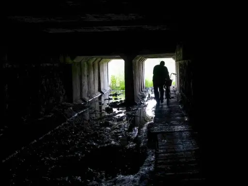 Mroczny tunel, błoto i woda. Postać z rowerem wychodzi ku światłu. Czy to początek drogi przez nawiedzone miejsca w Polsce?