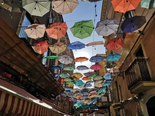 Kolorowe parasole nad ulicą w Katanii. Wspaniała instalacja, którą warto zobaczyć, tworzy magiczną atmosferę.