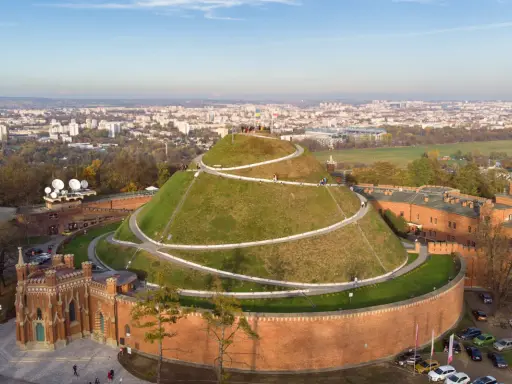 Kopiec Kościuszki w Krakowie, wspaniałe miejsce na darmowe atrakcje Kraków. Widok z lotu ptaka na zielony kopiec z krętymi ścieżkami i panoramę miasta.