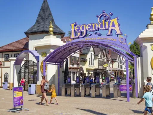 Wejście do Legendia Wesołe Miasteczko w Chorzowie. Rodziny wchodzą przez bramki, słońce świeci.
