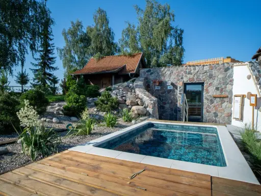 Relaks w polskim spa: basenik, kamienna ściana z wejściem do sauny i urokliwy ogród. Idealne miejsce na odpoczynek.
