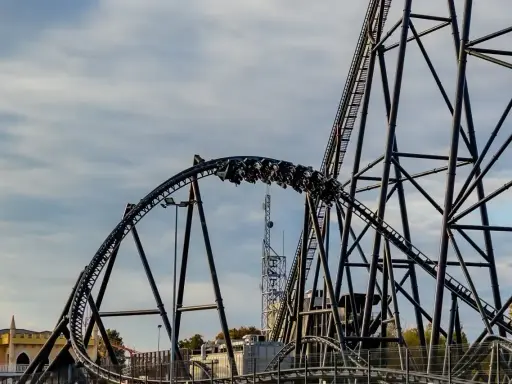 Pasażerowie jadą na wagonikach największego rollercoastera w Europie, który pnie się po stalowej konstrukcji.