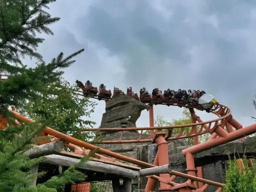 Kolejka górska w Legoland Polska pędzi po torach wśród zieleni i skalnych formacji.