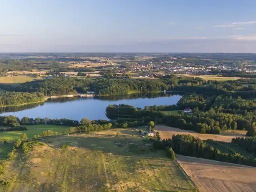 Malownicze jezioro otoczone lasami, z miasteczkiem w tle. Idealne miejsce na rodzinne wycieczki i odkrywanie bytów atrakcji dla dzieci.