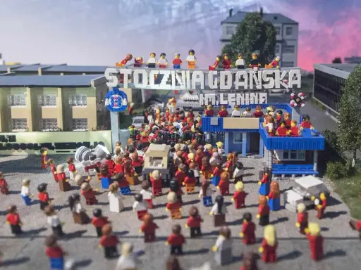 Miniaturowa scena z Klockoland Kraków przedstawiająca tłum ludzi pod bramą z napisem "Stocznia Gdańska im. Lenina".