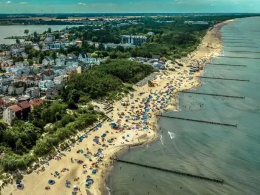 Tłum ludzi na plaży w Mielnie, cieszących się słońcem i morzem. To popularne **Mielno atrakcje** turystyczne.