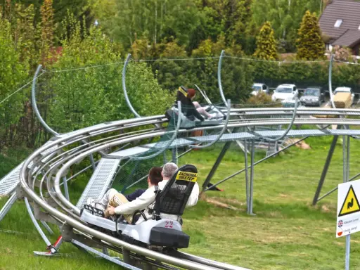 Wspaniały wyjazd z dzieckiem na weekend! Dwie osoby zjeżdżają na torze saneczkowym, ciesząc się widokami i adrenaliną.