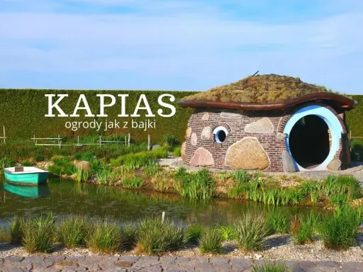 Bajkowy domek z kamienia i cegły, porośnięty trawą dach, otoczony zielenią i stawem. Ciekawe ogrody jak z bajki.
