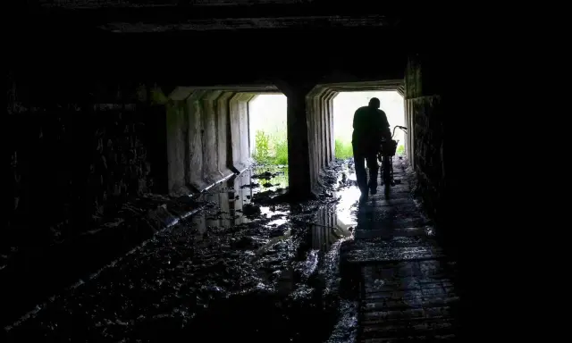 Mroczny tunel, błoto i woda. Postać z rowerem wychodzi ku światłu. Czy to początek drogi przez nawiedzone miejsca w Polsce?