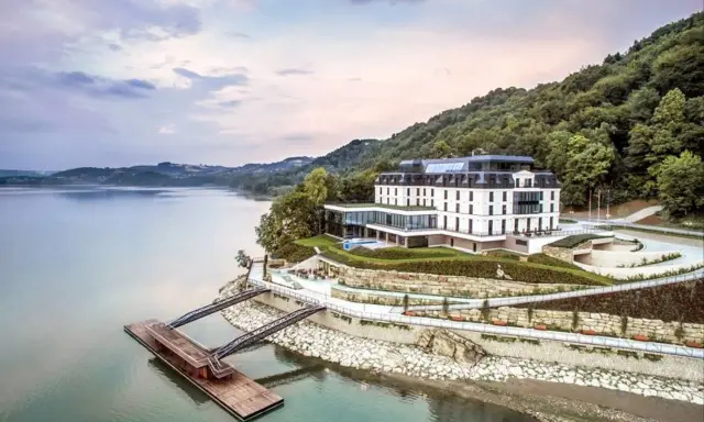 Elegancki hotel nad jeziorem, idealny na romantyczne miejsca w Polsce. Widok na spokojną taflę wody i zielone wzgórza.