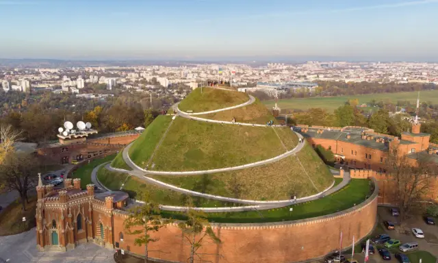 Kopiec Kościuszki w Krakowie, wspaniałe miejsce na darmowe atrakcje Kraków. Widok z lotu ptaka na zielony kopiec z krętymi ścieżkami i panoramę miasta.