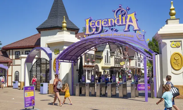 Wejście do Legendia Wesołe Miasteczko w Chorzowie. Rodziny wchodzą przez bramki, słońce świeci.