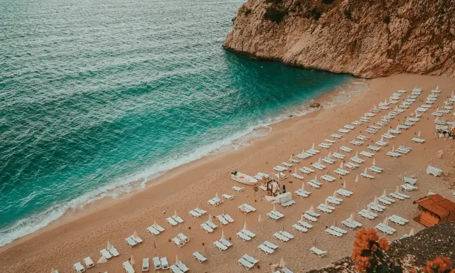 Piękna plaża z turkusową wodą i rzędami leżaków. Idealne miejsce, by zastanowić się, gdzie na wakacje.