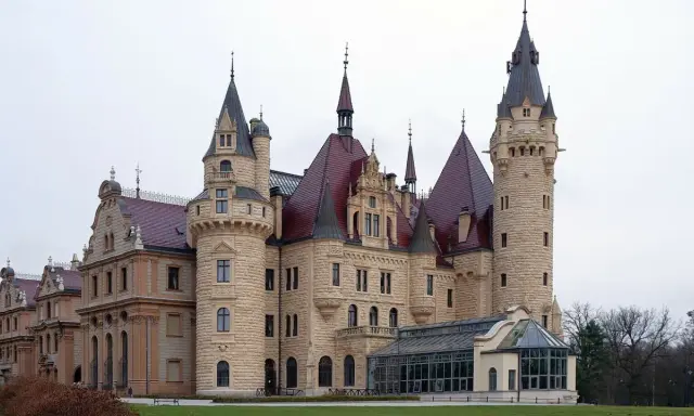 Zamek Książ, jeden z najpiękniejszych zamków w Polsce, z charakterystycznymi wieżami i czerwonymi dachami, otoczony zielenią.